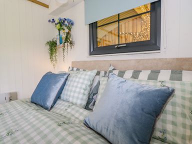 A bed with blue and green checkered bedding and pillows in a bedroom at High Rigg Shepherd's Sunrise in Brampton Cumbria
