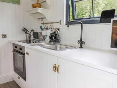 A kitchen countertop with a sink toaster kettle oven and utensils at High Rigg Shepherd's Sunrise in Brampton Cumbria