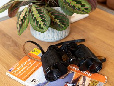 A table with a potted plant binoculars and an Ordnance Survey map of the English Lake District at Middle Longlands in Cartmel