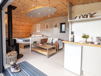 An open plan living area with a brown leather sofa coffee table and kitchenette at Middle Longlands in Cartmel