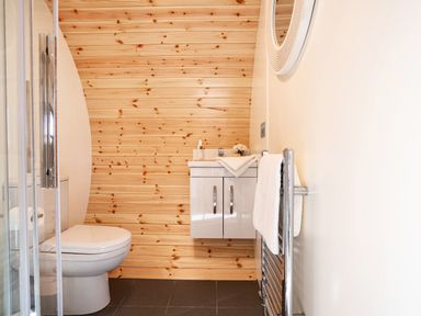 A bathroom with a toilet, white vanity cabinet, towel rail, and wooden panel wall at Middle Longlands in Cartmel