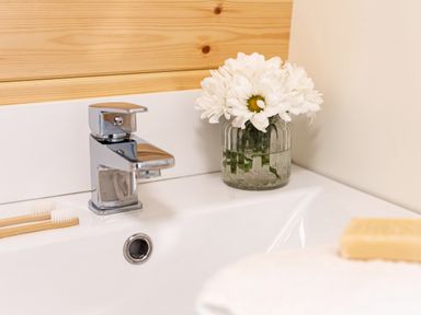 A bathroom sink with a faucet two toothbrushes a jar of white flowers and a bar of soap at Middle Longlands in Cartmel