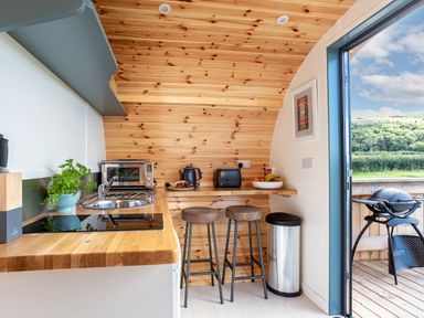 A compact kitchen with wooden countertops bar stools toaster and microwave at High Longlands in Cartmel