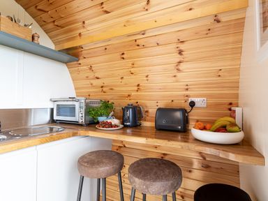 A kitchen corner with wooden walls and counter stools at High Longlands in Cartmel