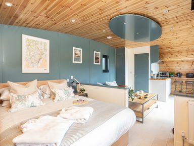 A bedroom with a bed and pillows next to a kitchen area with stools at High Longlands in Cartmel