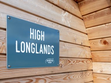 A blue sign reading High Longlands mounted on a wooden wall at High Longlands in Cartmel
