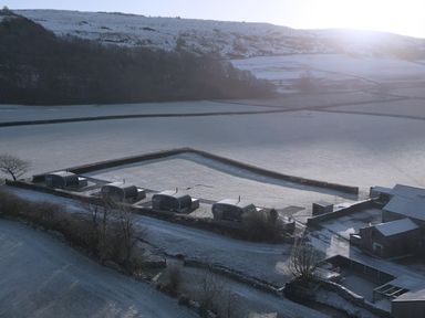 An outdoor view of huts and fields covered in snow at High Longlands in Cartmel