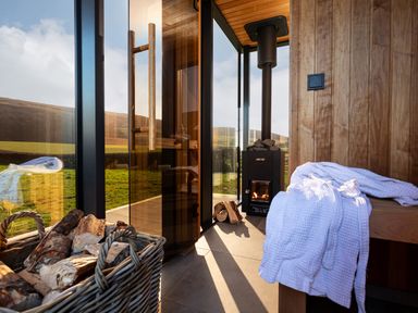 A space with a wood stove and a basket of logs at High Longlands in Cartmel