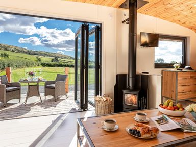 A kitchen with coffee and pastries on a table a wood stove and outdoor seating at Little Heaning in Cartmel