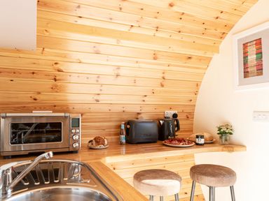 A kitchen counter with toaster kettle toaster oven bread and stools at Little Heaning in Cartmel
