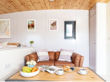 A sitting area with a brown leather sofa and a wooden coffee table with fruit cups and coffee at Little Heaning in Cartmel