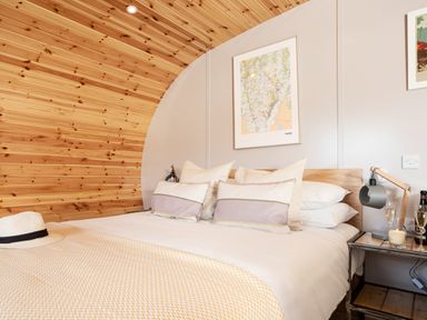 A bedroom with a bed pillows a nightstand lamp champagne glasses and a hat on the bed at Little Heaning in Cartmel