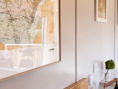 A framed map on a wall with a small plant in a glass jar on a shelf at Little Heaning in Cartmel