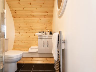 A bathroom with a white toilet white cabinet wooden wall and a towel on a heated rail at Little Heaning in Cartmel