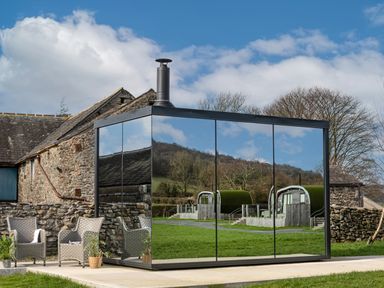 A glass building with seating near a stone wall at Little Heaning in Cartmel