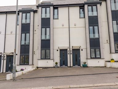 A row of modern townhouses with multiple floors and large windows at 6 Ocean Heights in Newquay