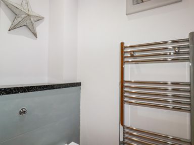 A bathroom corner with a chrome heated towel rail and a decorated wall with a star at 6 Ocean Heights in Newquay