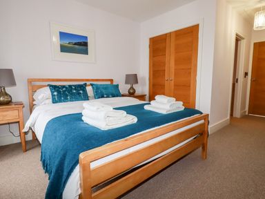 A bedroom with a wooden bed and bedside tables with lamps at 6 Ocean Heights in Newquay