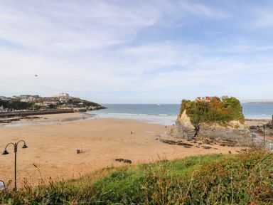 A beach with a rock formation and a house on top near the sea at 6 Ocean Heights in Newquay