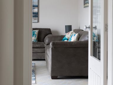 A living room with brown sofas and blue patterned cushions at Cartref in Benllech