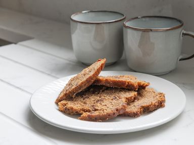 A plate with slices of brown bread and two grey mugs on a white surface at Cartref in Benllech
