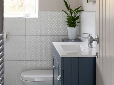 A bathroom with a white sink and blue cabinet a white toilet and a plant in a white pot at Cartref in Benllech