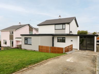 A two story house with a driveway and a wooden fence at Daresfield in Cemaes Bay