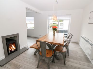 A dining area with a wooden table and metal chairs next to a fireplace at Daresfield in Cemaes Bay