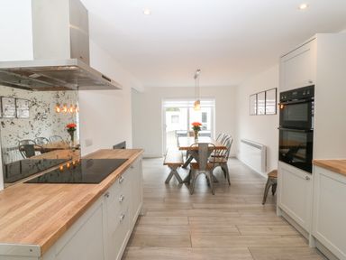 A kitchen with wooden countertops a dining table with metal chairs and flowers at Daresfield in Cemaes Bay