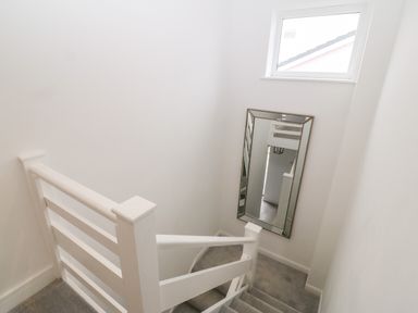 A white staircase with carpeted steps and a large wall mirror at Daresfield in Cemaes Bay