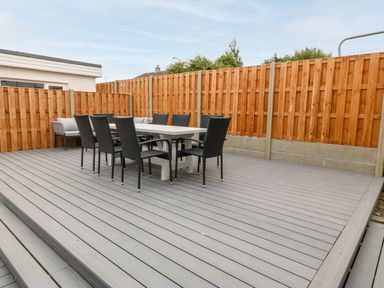 An outdoor deck area with a rectangular table and black chairs surrounded by wooden fencing at Daresfield in Cemaes Bay