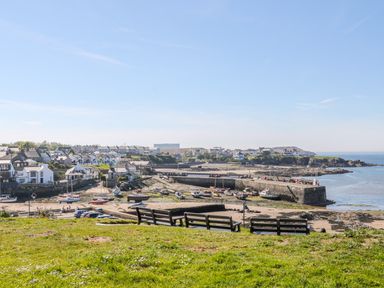 A coastal village with boats on a beach and benches on grass at Daresfield in Cemaes Bay