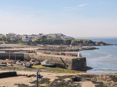 A harbor with boats docked and houses on a hill by the sea at Daresfield in Cemaes Bay