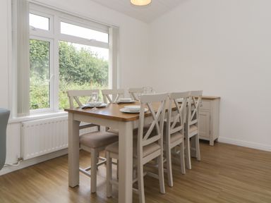 A dining area with a wooden table set for six near a window at Harcombe House Bungalow 11 in Chudleigh