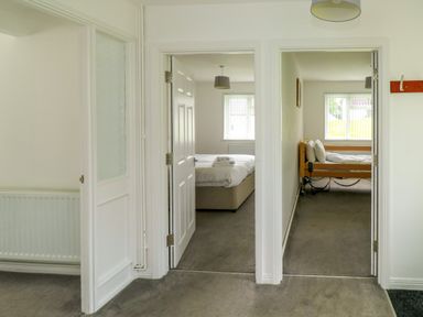 A hallway with two open doors showing bedrooms with beds at Harcombe House Bungalow 11 in Chudleigh