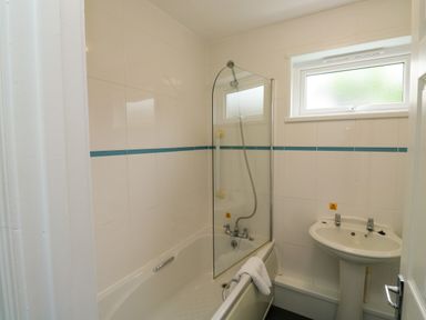 A bathroom with a bathtub shower combination and a pedestal sink at Harcombe House Bungalow 11 in Chudleigh