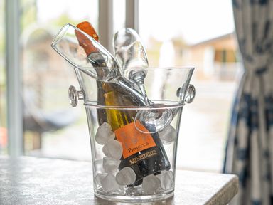 A champagne bottle and two glasses in an ice bucket on a table at Loluke Lodge on The Lake 5 Coniston Drive Borwick near Carnforth