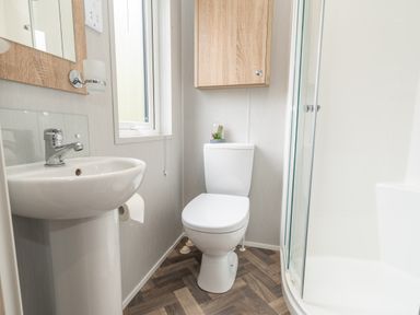 A bathroom with a sink toilet shower and wooden cabinet at Loluke Lodge on The Lake 5 Coniston Drive Borwick near Carnforth