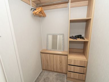 A small closet with wooden shelves hangers a mirror and hairbrushes with a hairdryer at Loluke Lodge on The Lake 5 Coniston Drive Borwick near Carnforth