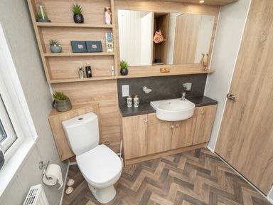 A bathroom with a toilet sink cabinets and shelving at Loluke Lodge on The Lake 5 Coniston Drive Borwick near Carnforth