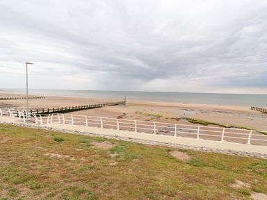 A sandy beach with sea defenses and a walkway with railings at Ty Uchaf in Rhyl