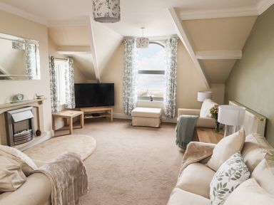 A living room with two sofas a television on a stand and a fireplace at Ty Uchaf in Rhyl