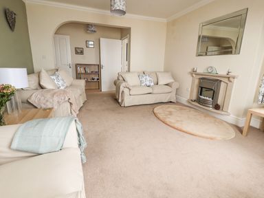 A living room with two sofas a fireplace a mirror and a small bookshelf at Ty Uchaf in Rhyl