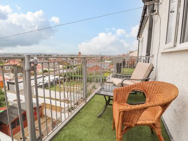 A balcony with artificial grass and two chairs overlooking rooftops at Ty Uchaf in Rhyl