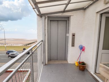 A small outdoor balcony with an elevator door a metal railing and a potted plant with nets at Ty Uchaf in Rhyl