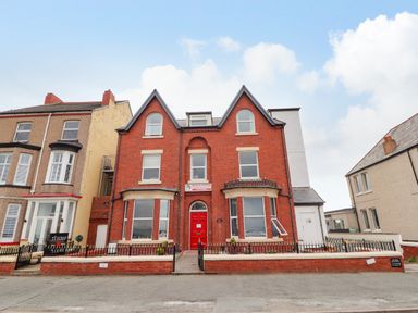 A red brick building with a red door and iron fences at Ty Uchaf in Rhyl