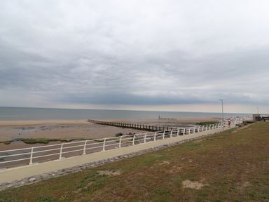 A beach with a walkway and white railing near the sea at Ty Uchaf in Rhyl