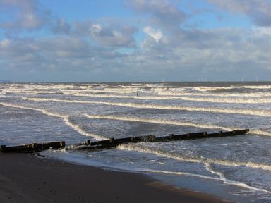 A beach with waves and wooden groynes extending into the sea at Ty Uchaf in Rhyl