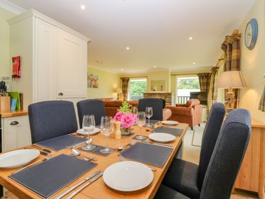 A dining table set with plates glasses and cutlery in an open plan kitchen and living room at The Lodge in Blairgowrie