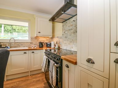A kitchen with cream cabinets wooden countertops a black stove and a window showing outside at The Lodge in Blairgowrie